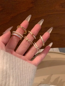 Close-up of golden stackable rings featuring pearls, crystals and luxury H-letter designs