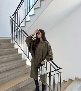 Detail of dark green suede two-piece set featuring loose long-sleeve jacket and shorts