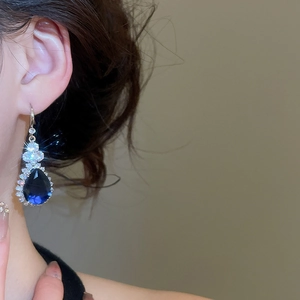 Close-up of elegant teardrop blue sapphire earrings with sparkling zircon halo setting