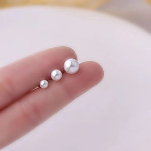 Titanium steel pearl stud earrings in three sizes shown on fingers for scale