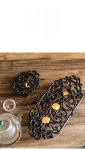 Detail of vintage black cast iron candle warmer base with hollow vine pattern texture