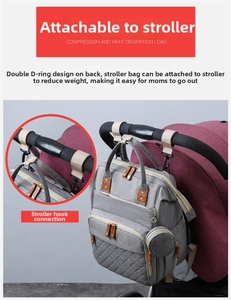 Detail of light grey diaper bag attached to a red stroller with hooks and D-rings