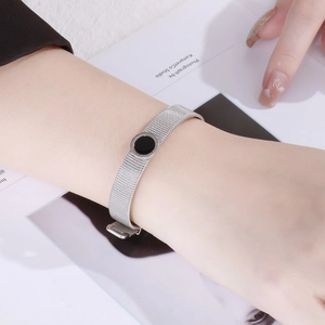 Close-up of adjustable silver mesh bracelet with Roman numeral black disc charm in 18k steel