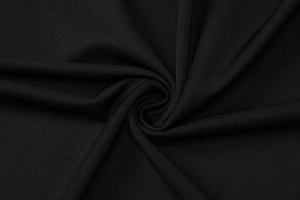 Macro shot of black knitted fabric texture showing soft pleats and premium drape