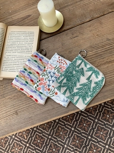 Three cotton linen pouches with floral embroidery on rustic wooden background