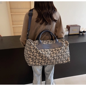 Vista posteriore di una modella con borsa da viaggio grande a motivi geometrici al caffè
