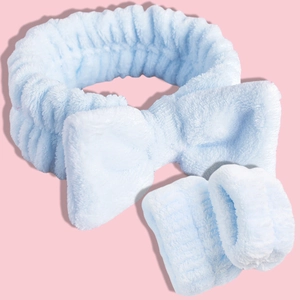 Macro shot of light blue coral fleece headband and wristbands set on pink background