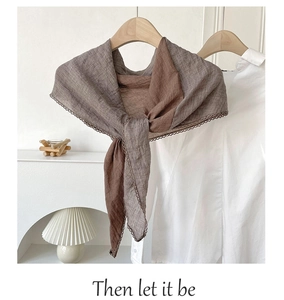 Detail of linen scarf with brown color block and delicate lace trim on wooden hanger