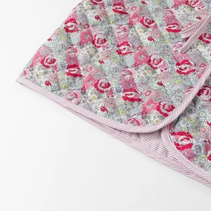Close-up of quilted floral fabric with a vintage pink pattern and striped piping edge