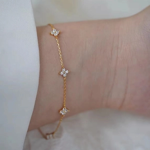 Detailed close-up of clover bracelet with zircon stones worn on the wrist in golden finish