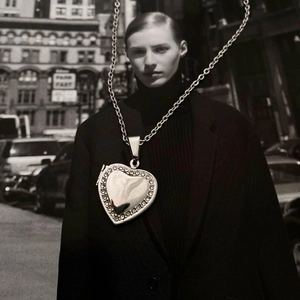 Detail of silver heart locket pendant with rhinestone edges on a thick link chain