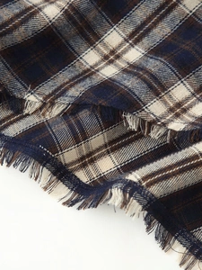 Detail of plaid dress showing raw fringe hem and classic navy brown woven fabric texture
