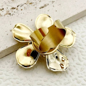 Close-up of a golden flower ring with coral and white crystal zircon on white stone