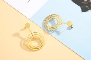 Detailed view of layered titanium steel round hoop earrings in polished gold finish