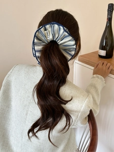 Detailed view of blue and white striped fabric scrunchie with AY Jewelry label on ponytail