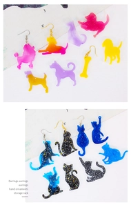Macro detail of acrylic animal earrings featuring glitter cat and dog shapes