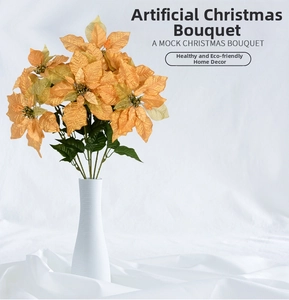 Close-up of champagne gold silk poinsettia bouquet in a white textured ceramic vase