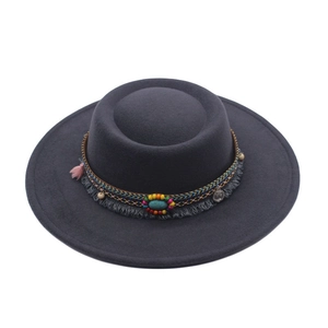 Detail of dark grey flat top hat featuring ethnic woven band with beads and tassels