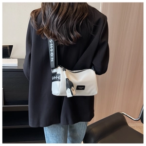 Gros plan du sac bandoulière cylindrique blanc avec large sangle imprimée sur un modèle
