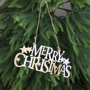 Detail of wooden Merry Christmas sign hanging on pine branch with stars and rustic twine