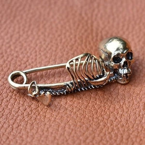 Vintage Gothic skull safety pin brooch in antique brass finish on leather background