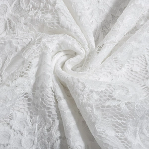 Detailed macro shot of white floral lace fabric with intricate embroidery and mesh texture
