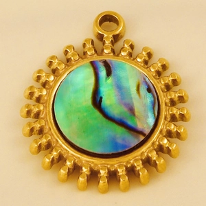 Macro detail of sunburst pendant featuring iridescent abalone shell inlay in gold setting