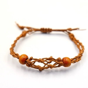 Detalle de pulsera artesanal de cuerda marrón tejida con cuentas de madera naranja y nudo ajustable