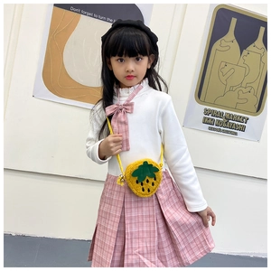 Detailed close-up of a strawberry plush bag paired with a pink plaid school skirt