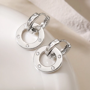 Polished silver geometric hoop earrings with sparkling cubic zirconia on white stand