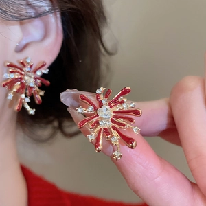 Detail of elegant red firework earrings with gold plating and cubic zirconia inlay