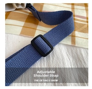 Detail of adjustable blue woven strap and buckle on the off-white canvas bag