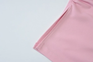 Détail rapproché d'un haut rose montrant les coutures et la texture du tissu en maille
