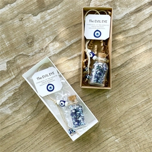 Detailed view of Evil Eye wish bottles with glass beads in white and brown gift boxes