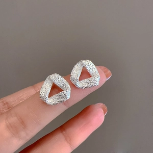 Matte silver geometric triangle stud earrings held by hand for scale and texture