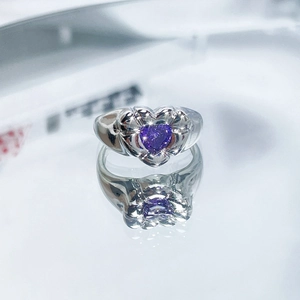Macro shot of a silver heart-shaped purple zircon ring with a clear reflection