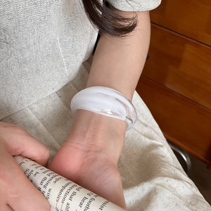 Close-up of white marble pattern resin wide cuff bracelet on model wrist with retro vibe