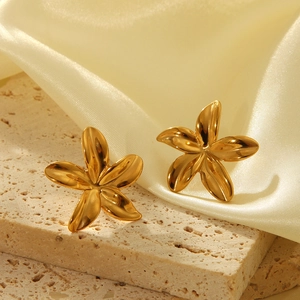 Détail macro de boucles d'oreilles tournesol dorées sur pierre et fond satiné