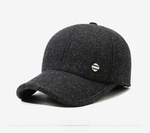 Detail view of dark gray wool baseball cap with metallic logo badge and thick fabric texture