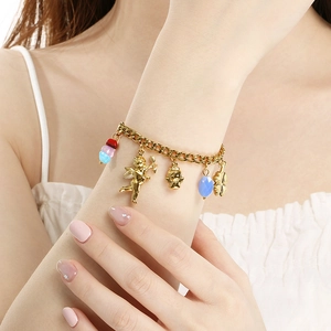 Detail of gold-plated Cuban link bracelet featuring Cupid, angel and clover pendants
