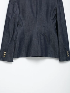 Dettaglio di un blazer in denim blu scuro con bottoni dorati decorativi sui polsini