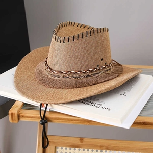 Detail view of woven straw cowboy hat with brown tassel, gold chain and windproof cord