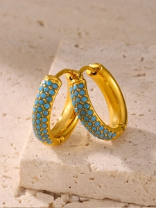 Detail of gold huggie hoop earrings featuring triple rows of inlaid blue turquoise stones