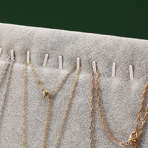 Vertical grey velvet jewelry stand with hooks displaying gold and silver necklaces
