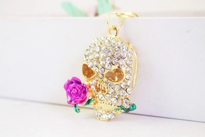 Detail view of gold skull keychain with purple enamel rose and sparkling rhinestones