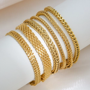 Set of 18K gold plated stainless steel Cuban and snake chain bracelets on a display