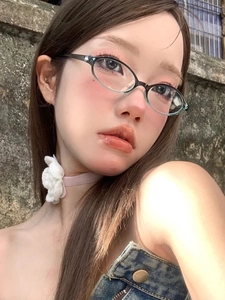 Detailed close-up of retro oval glasses with thin black frames and light blue gradient lenses