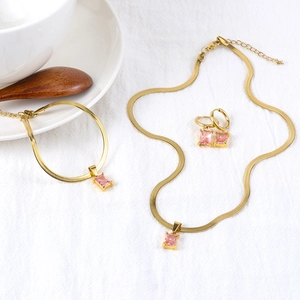 Detalle de conjunto de collar y pulsera dorados con gemas cuadradas de color rosa