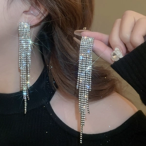 Detail showing long silver tassel earrings with sparkling rhinestones on an ear