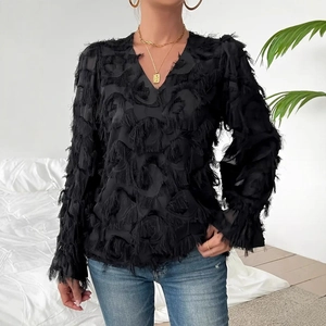 Detail of elegant black long-sleeve V-neck blouse with textured fringe and feather accents